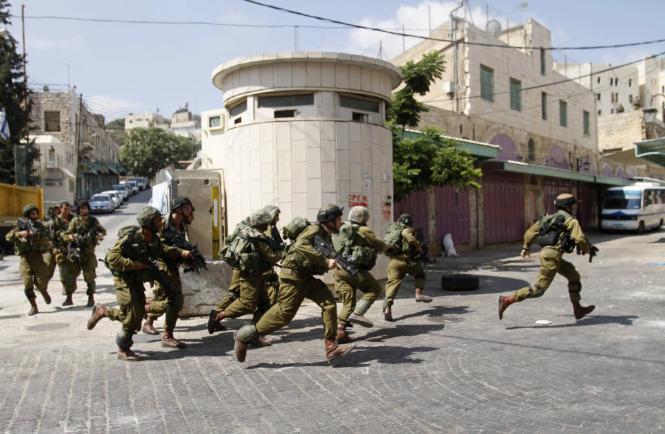 Israeli soldiers run after Palestinian stone throwers, not seen, in the Israeli-controlled area of the West Bank city of Hebron, Monday, Sept. 10, 2012. Palestinian demonstrators fed up with high prices and unpaid salaries shuttered shops, halted traffic with burning tires and closed schools throughout the West Bank on Monday in the largest show of popular discontent with the governing Palestinian Authority in its 18-year history. (AP Photo/Nasser Shiyoukhi)