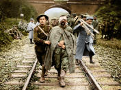 <p>A British soldier marches a wounded German along a railway track in 1916. (Tom Marshall/mediadrumworld.com) </p>