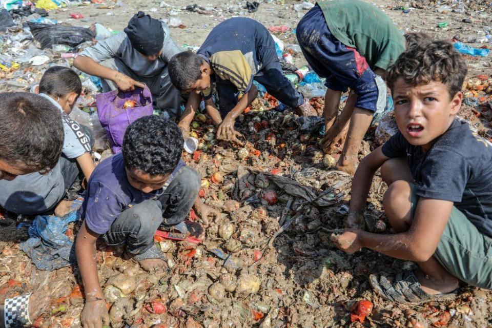 Un grupo de niños busca comida en la basura.