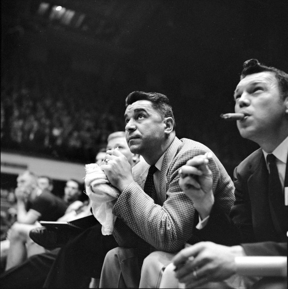 An assistant coach lights up a cigar on the bench as Clemson coach Press Maravich works his trademark towel during a game in the 1957 ACC Tournament in Reynolds Coliseum.