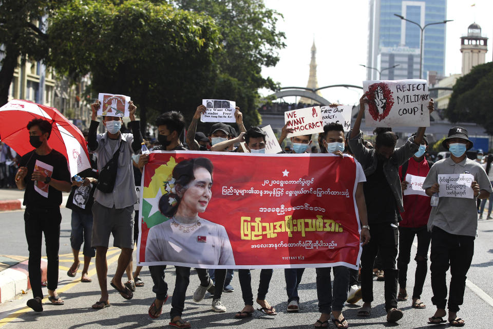 Protesters hold a banner with an image of deposed Myanmar leader Aung San Suu Kyi as they march in Yangon, Myanmar on Monday, Feb. 8, 2021. Tension in the confrontations between the authorities and demonstrators against last week's coup in Myanmar boiled over Monday, as police fired a water cannon at peaceful protesters in the capital Naypyitaw. (AP Photo)