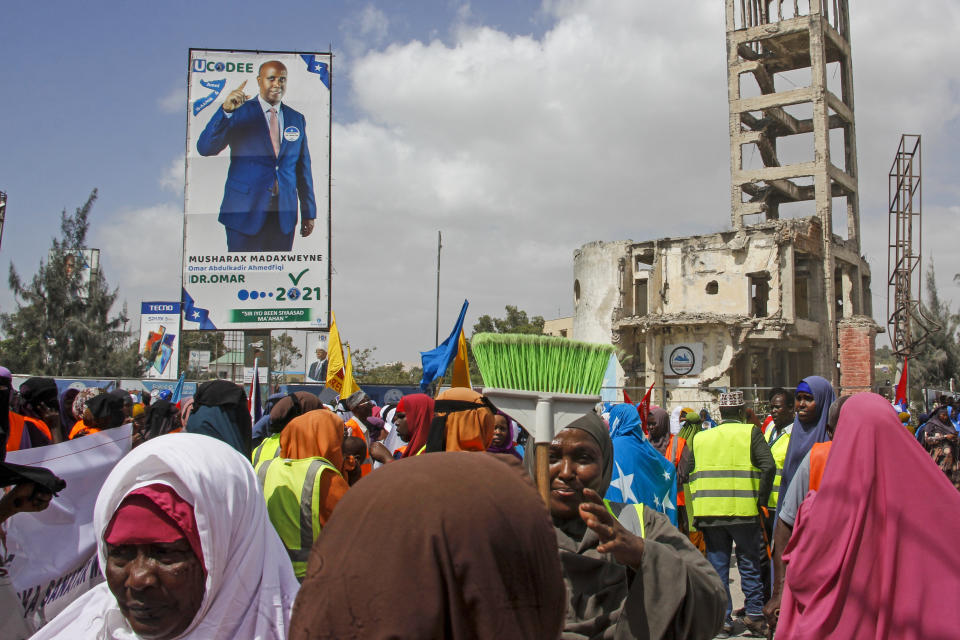 Somalis walk past a billboard showing candidate Omar Abdulkadir Ahmedfiqi in Mogadishu, Somalia Friday, Jan. 29, 2021. As Somalia marks three decades since a dictator fell and chaos engulfed the country, the government is set to hold a troubled national election but two regional states are refusing to take part in the vote to elect Somalia's president and time is running out before the Feb. 8 date on which mandates expire. (AP Photo/Farah Abdi Warsameh)