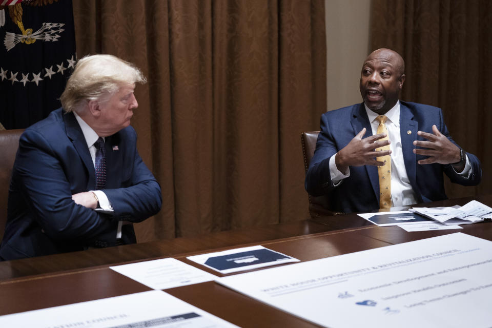 FILE - President Donald Trump listens as Sen. Tim Scott, R-S.C., speaks during a meeting on opportunity zones in the Cabinet Room of the White House in Washington, May 18, 2020. Scott has filed paperwork to enter the 2024 Republican presidential race. He'll be testing whether a more optimistic vision of America’s future can resonate with GOP voters who have elevated partisan brawlers in recent years. (AP Photo/Evan Vucci, File)