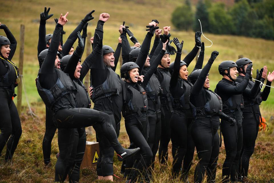 The Traitors US season two cast in black west suits and helmets cheering after a mission