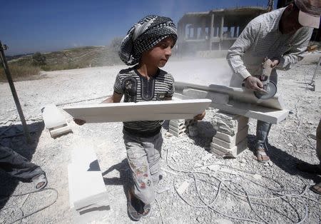 A Syrian refugee child works with his father in the south of Sidon, southern Lebanon April 30, 2014. REUTERS/Ali Hashisho