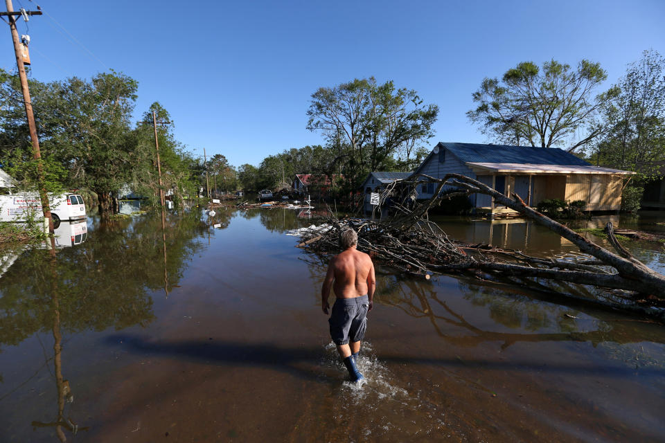 Image: Brian Schexnayder walks down a flooded street after Hurricane Delta in Iowa (Jonathan Bachman / Reuters)