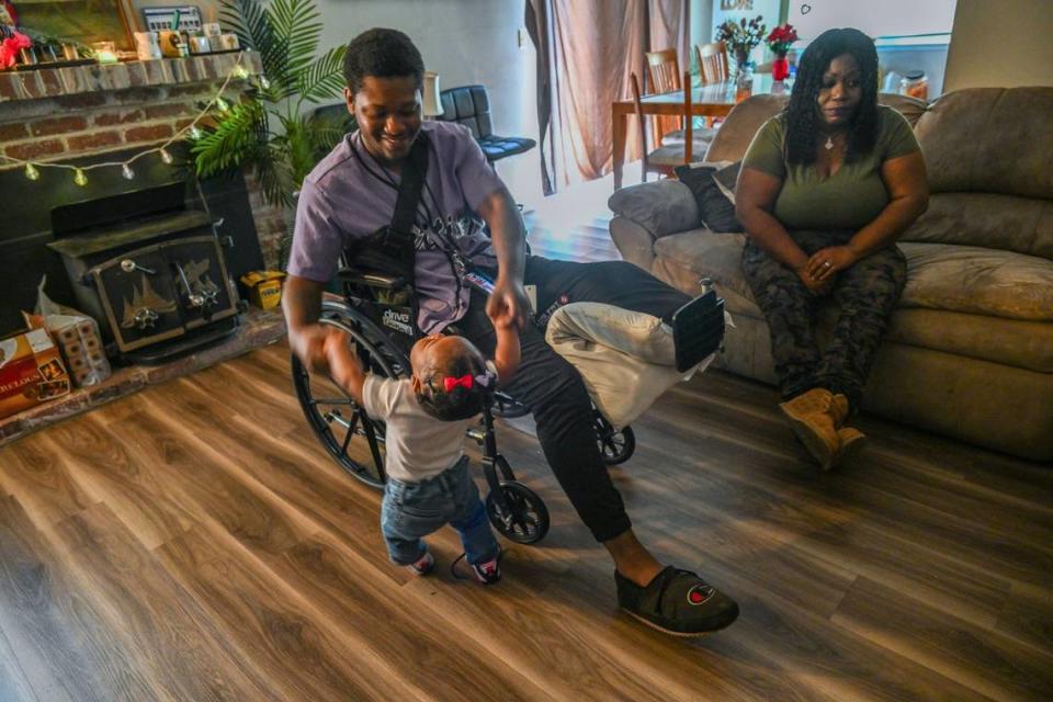 Dirk Couvson, 20, plays with his daughter Kaili, 1, last month as his mother Lythia Bouie worries about the emotional and financial hardship he faces after he lost his left leg in an accident. “They should figure out something about that street – it seems dangerous,” he said.