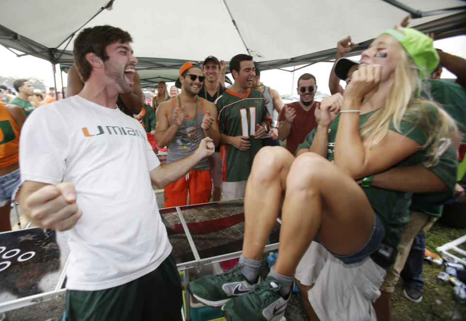 In this Saturday, Nov. 9, 2013 photo, Jack Murphy, left, 20, celebrates after wining a game of pong while tailgating before the start of an NCAA college football game between Miami and Virginia Tech, in Miami Gardens, Fla. It may be the hottest tailgate party at the University of Miami's homecoming game, but the 100-yard stretch of free pizza and party tents set up by Generation Opportunity, a national conservative organization, is also a carefully crafted strategy aimed at getting students to opt out of President Barack Obama's controversial new health law. (AP Photo/Wilfredo Lee)