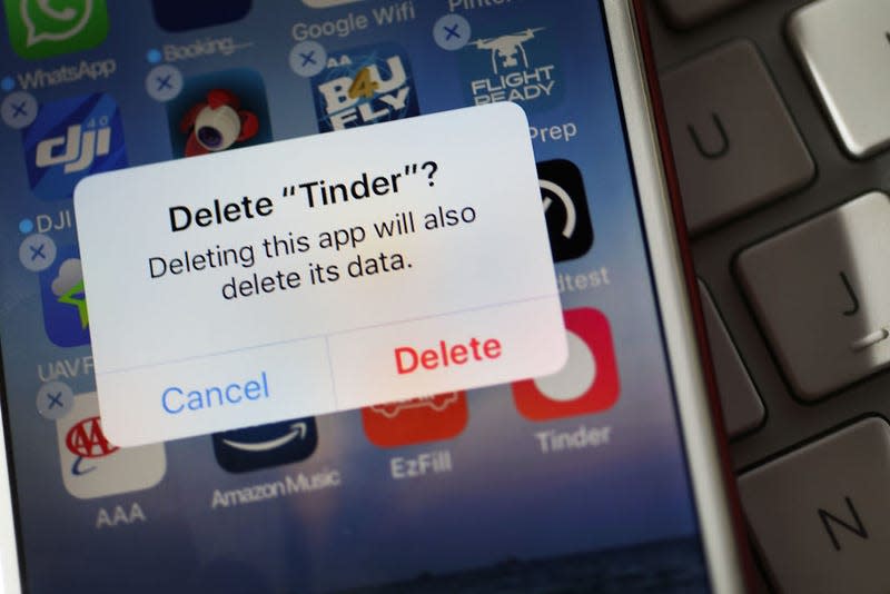 A photo of an iPhone prompting the user to delete Tinder.