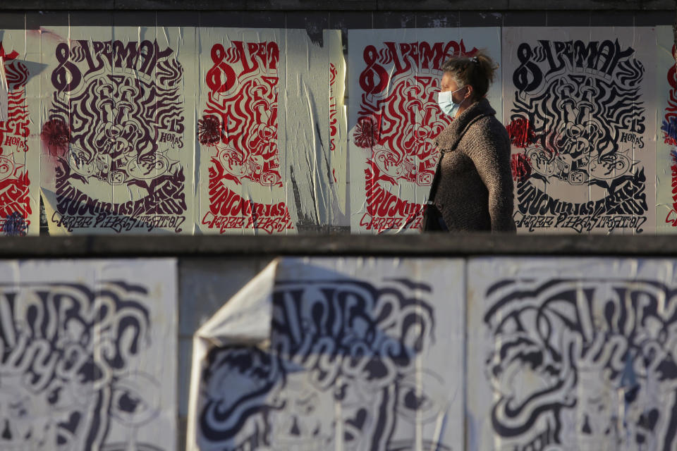 A woman wearing a face mask stands at a bus stopt in Lisbon, Friday, Oct. 16, 2020. Portugal has seen a steady increase in cases of COVID-19 in the past weeks. (AP Photo/Armando Franca)