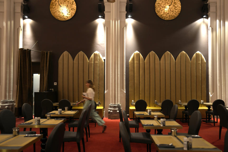 A woman walks through the dining room of the Martin's Patershof hotel in the center of Mechelen, Belgium, Monday, June 19, 2023. Across Europe, the continent that nurtured Christianity for most of two millennia, many churches, convents, beguinages and chapels stand empty as faith and church attendance have dwindled over the past half century. Many are now been repurposed to preserve their historical and architectural relevance, while others have opened up to non-religious activities to expand their use. (AP Photo/Virginia Mayo)