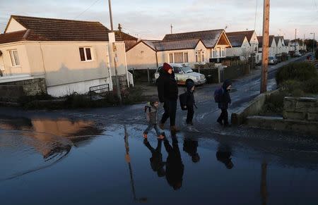 Residents walk through the village of Jaywick which is threatened by a storm surge, in Essex, Britain January 13, 2017. REUTERS/Stefan Wermuth