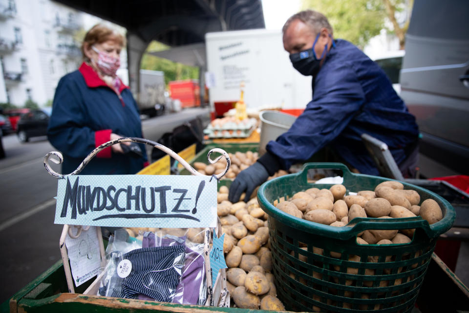 28 April 2020, Hamburg: A market trader at Isemarkt offers not only his potatoes and eggs but also the handmade mouthguard of a colleague. Photo: Christian Charisius/dpa (Photo by Christian Charisius/picture alliance via Getty Images)