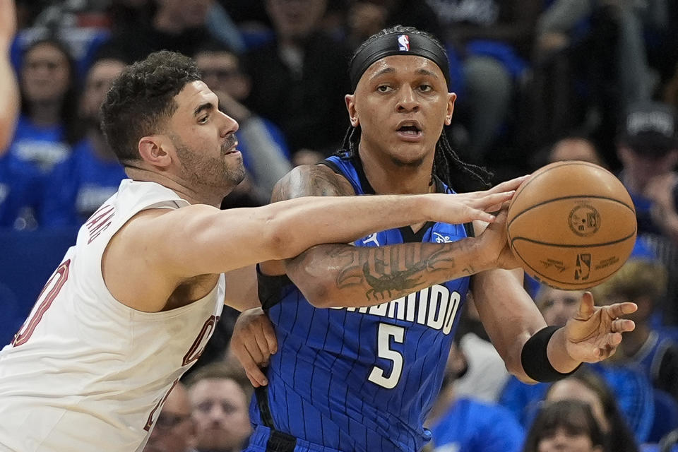 Cleveland Cavaliers forward Georges Niang, left, tries to block a pass by Orlando Magic forward Paolo Banchero (5) during the first half of Game 3 of an NBA basketball first-round playoff series Thursday, April 25, 2024, in Orlando, Fla. (AP Photo/John Raoux)