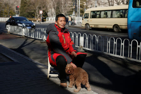 A public security volunteer poses with his dog as he keeps watch in a street ahead of the upcoming plenary session of National People's Congress (NPC), China's parliamentary body, in Beijing, China, March 1, 2018. REUTERS/Thomas Peter