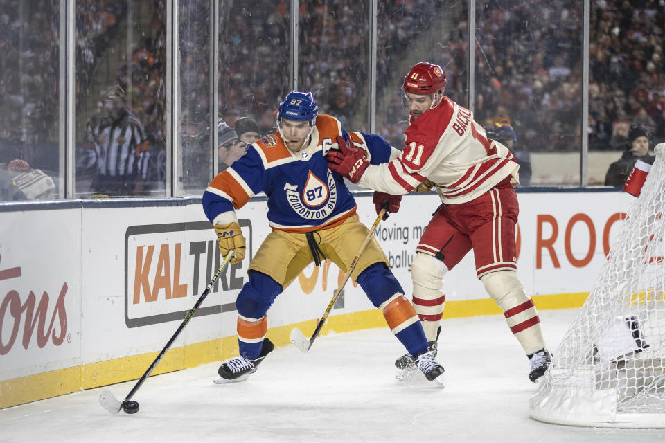 Calgary Flames' Mikael Backlund (11) and Edmonton Oilers' Connor McDavid (97) battle for the puck during third-period NHL Heritage Classic outdoor hockey game action in Edmonton, Alberta, Sunday, Oct. 29, 2023. (Jason Franson/The Canadian Press via AP)