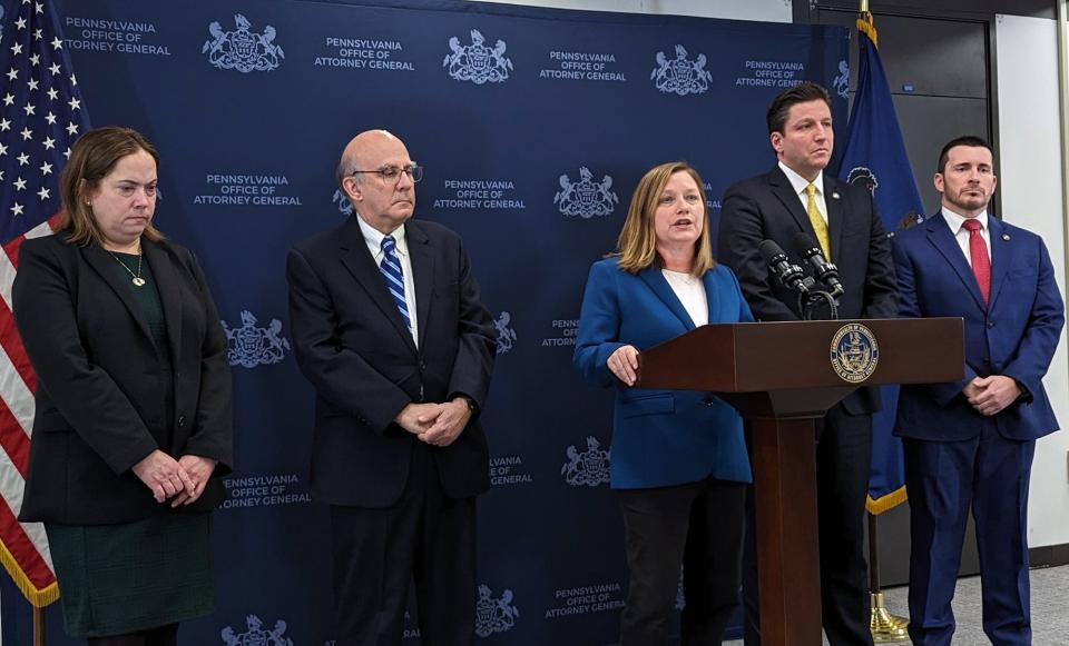 Members of the investigative team surround Acting Pennsylvania Attorney General Michelle Henry at the podium while she announces the filing of criminal charges against five individuals associated with Jehovah Witness congregations on Tuesday in Harrisburg.