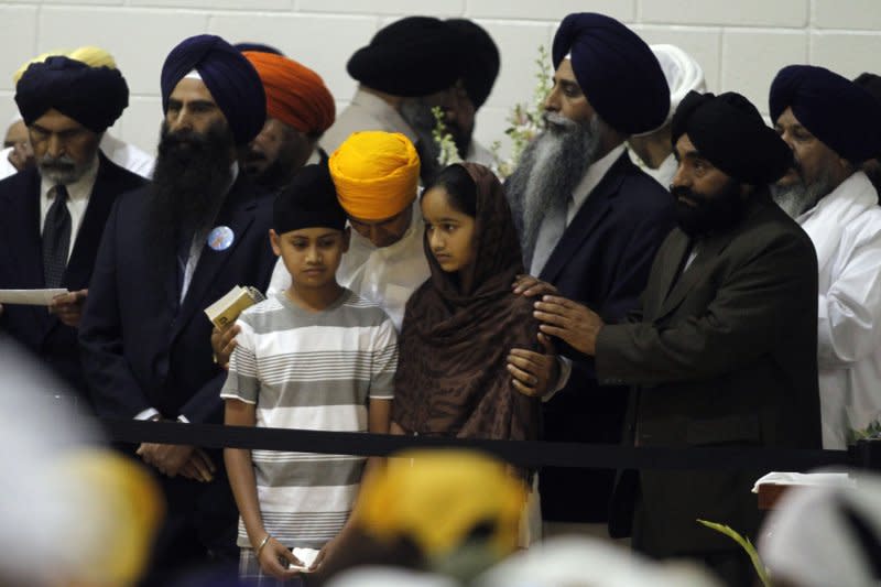 The 11-year-old son and 12-year-old daughter of shooting victim Prakash Singh are are comforted by mourners at a memorial service and visitation August 10, 2012, for six members of the Sikh temple mass murder at Oak Creek High School in Oak Creek, Wis. Wade Michael Page, a member of a racist neo-nazi group, has been identified as the lone gunman who killed six people, and then himself, during Sunday services at the Sikh Temple August 5. File Photo by Allen Fredrickson/UPI