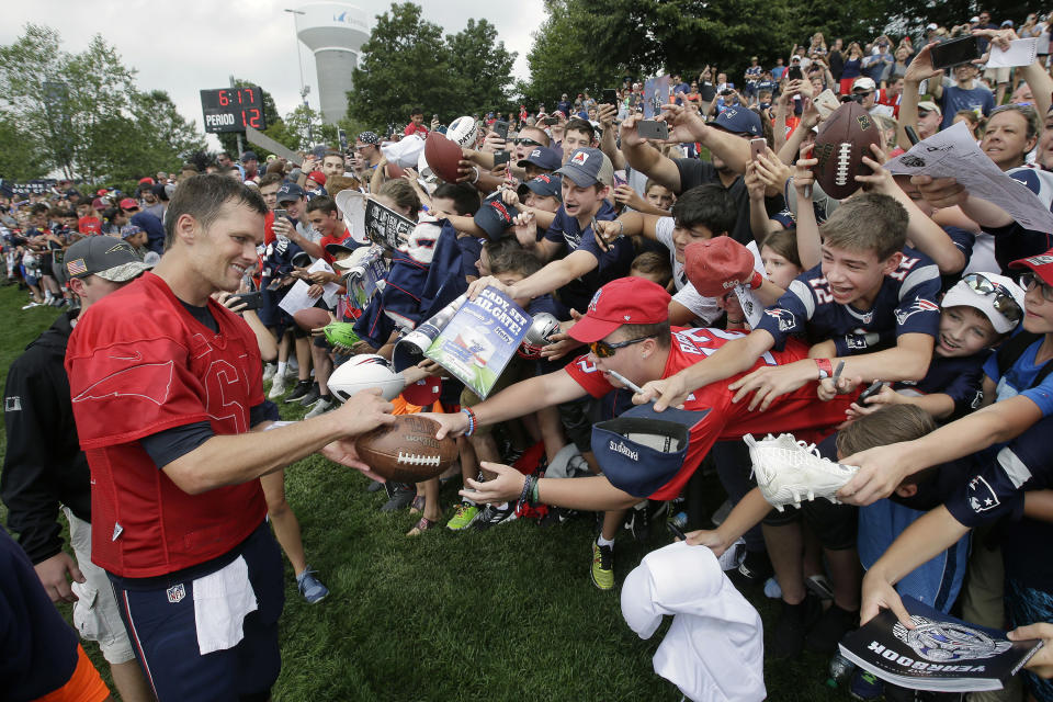 FILE - In this Aug. 3, 2017, file photo, New England Patriots' Tom Brady, left, signs autographs for fans at NFL football training camp in Foxborough, Mass. Tom Brady is an NFL free agent for the first time in his career. The 42-year-old quarterback with six Super Bowl rings said Tuesday morning, March 17, 2020, that he is leaving the New England Patriots. (AP Photo/Steven Senne)