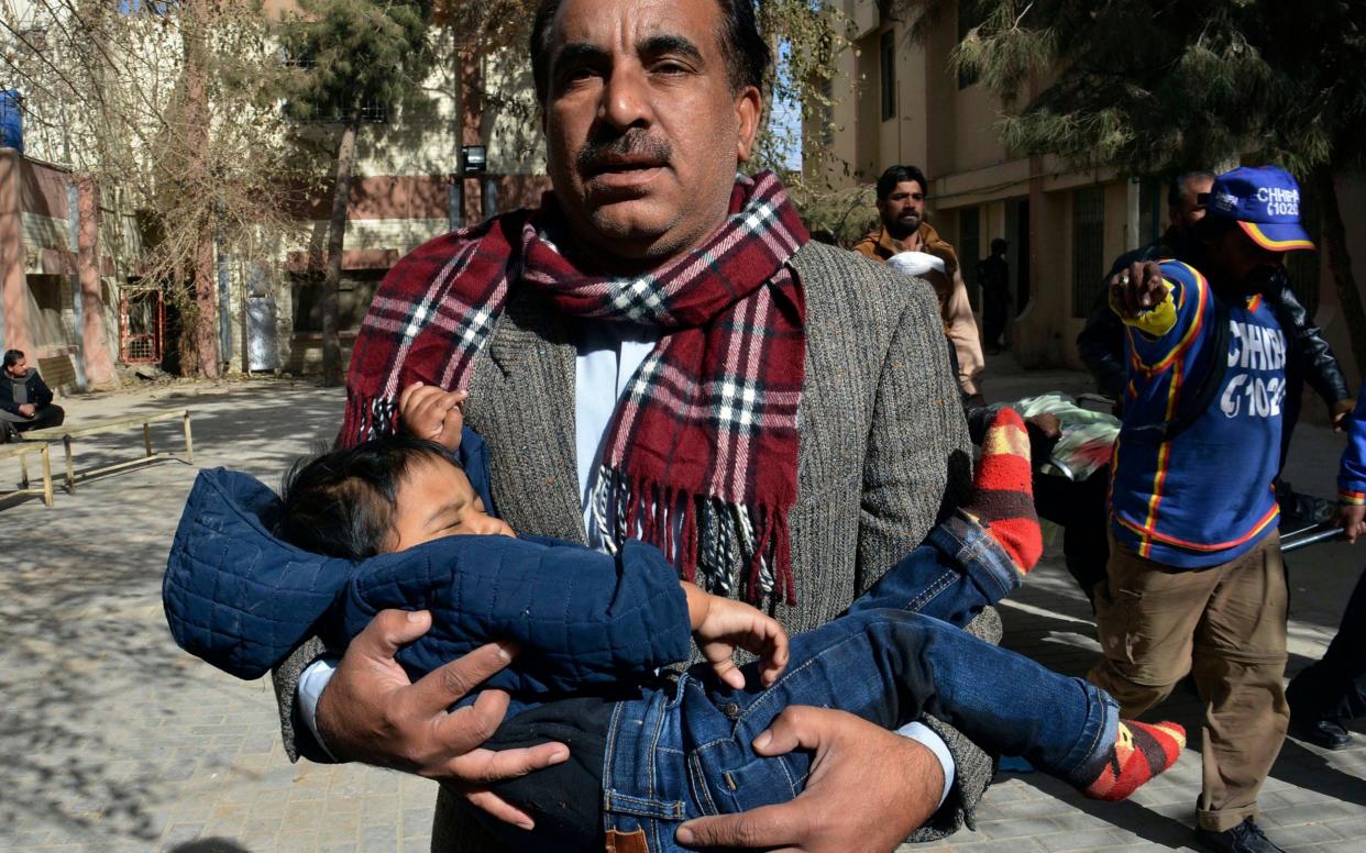 A volunteer rescues a child while others removing a body following the suicide attack on a church in Quetta - AP