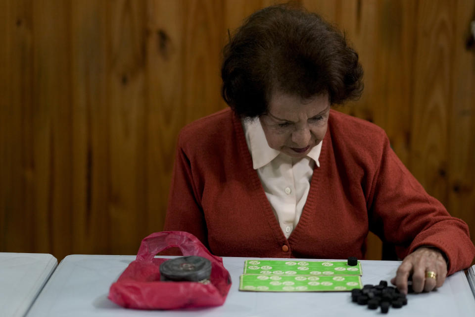 Mercedes Villafane, 80, plays bingo at the Caballito and Villa Crespo, a recreational day center for retirees, in Buenos Aires, Argentina, Wednesday, April 12, 2023. Villafane said that when retirees go shopping, they can never afford to purchase items by weights, but rather one or two products at a time. (AP Photo/Natacha Pisarenko)