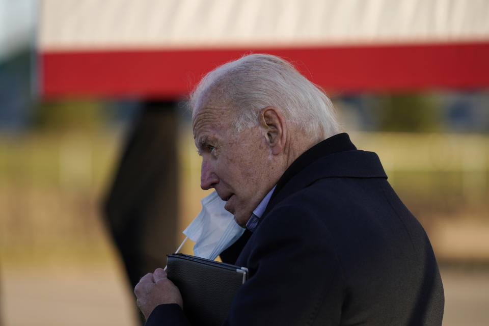 Democratic presidential candidate former Vice President Joe Biden puts on a face mask during a rally at the Minnesota State Fairgrounds in St. Paul, Minn., Friday, Oct. 30, 2020. (AP Photo/Andrew Harnik)