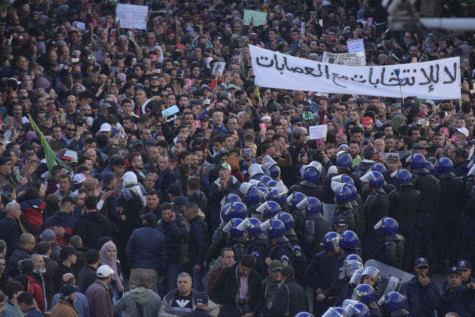 Algerian demonstrators take to the streets in the capital Algiers to protest against the government and reject the upcoming presidential elections, in Algeria, Wednesday, Dec. 11, 2019. Algeria's powerful army chief promises that a presidential election on Thursday will define the contours of a new era for a nation where the highest office has stood vacant for eight months. The tenacious pro-democracy movement which forced leader Abdelaziz Bouteflika to resign after 20 years in power doesn't trust the confident claim and is boycotting the vote. Banner in Arabic reads "No to election with the gangsters." (AP Photo/Toufik Doudou)