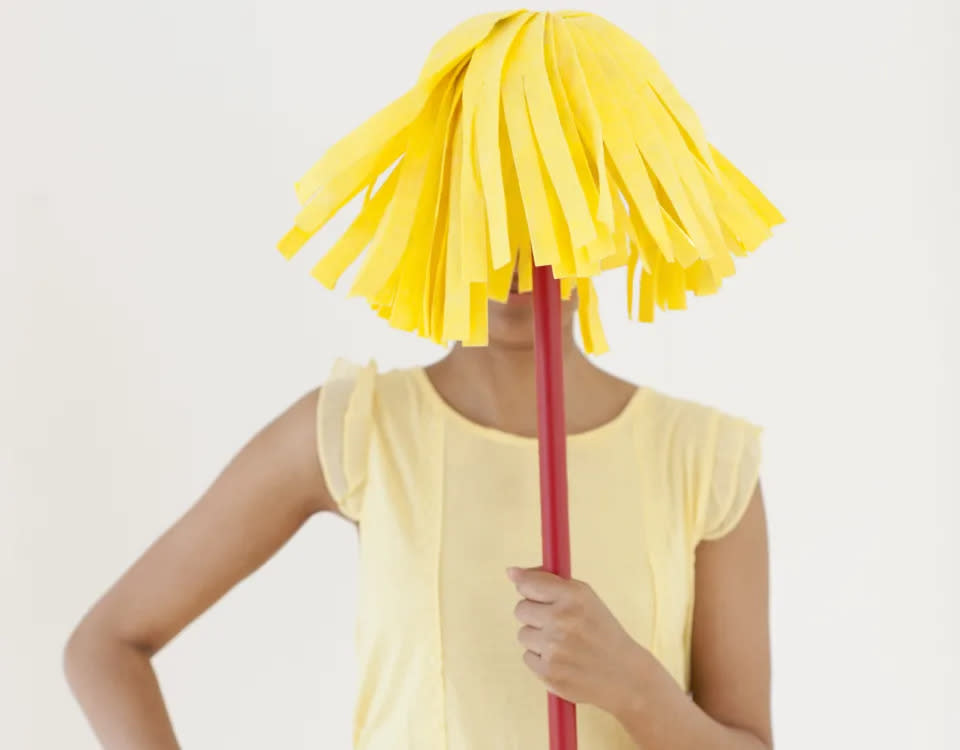 Person hiding face behind a yellow mop.