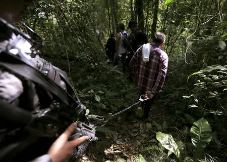 A prison guard escorts a handcuffed inmate, who is looking for a pit, as they walk in a rural area close to Chaguani, Colombia, June 18, 2015. REUTERS/Jose Miguel Gomez