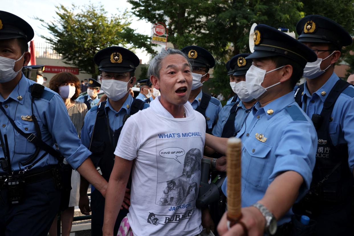 Police officers escort a protester protesting against the Tokyo 2020 Olympic Games after he got into an argument with a supporter of the Olympic Games near the Olympic Stadium in Tokyo on July 23, 2021, ahead of the opening ceremony of the 2020 Tokyo Olympic Games. (Photo by Yuki IWAMURA / AFP) (Photo by YUKI IWAMURA/AFP via Getty Images)