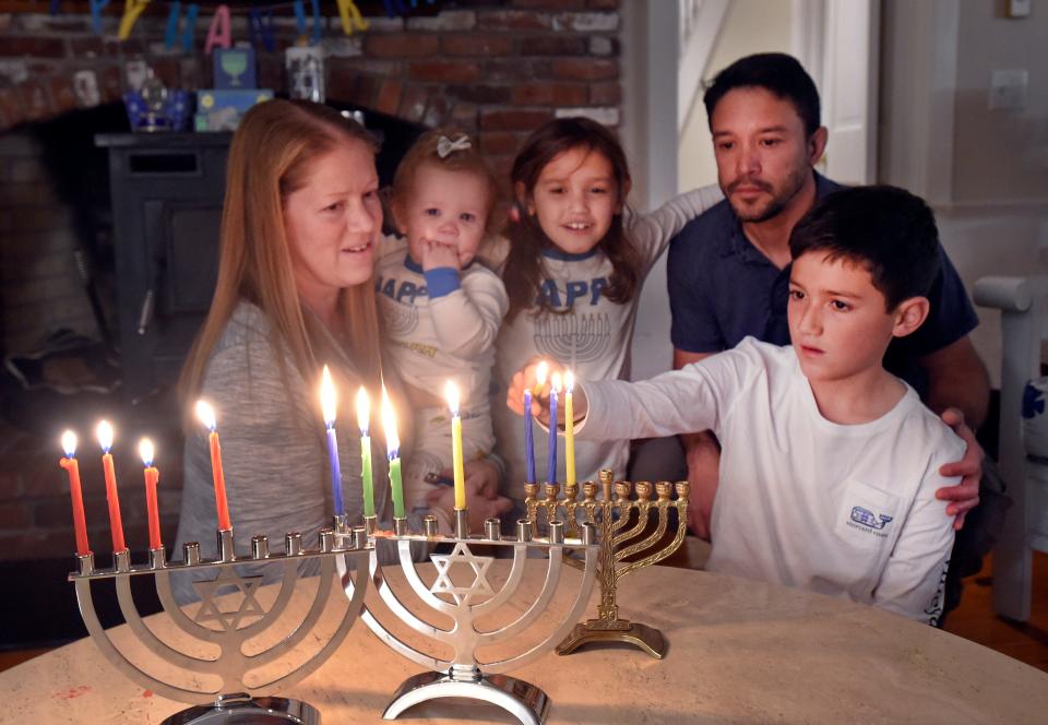 Eleven-year-old Ben lights a candle on the menorah for Hanukkah at the De La Vega home in Orleans. Parents Melissa and Marcus are joined by their other two children, Rebecca,8, and Maggie,14 months.