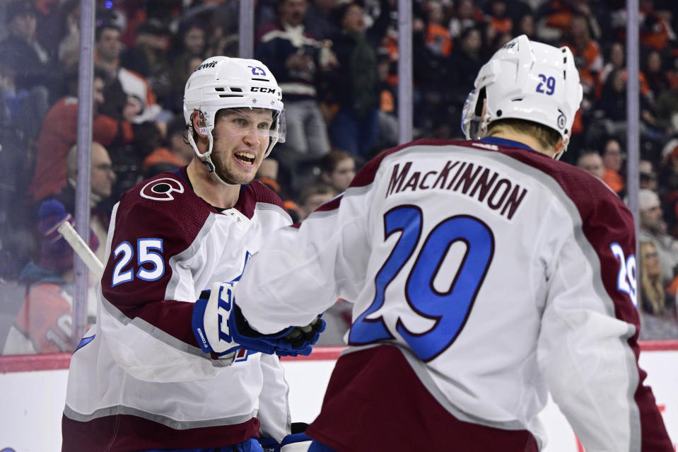 Colorado Avalanche's Logan O'Connor, left, celebrates with Nathan MacKinnon (29) after scoring an empty net goal for a hat trick during the third period of an NHL hockey game against the Philadelphia Flyers, Saturday, Jan. 20, 2024, in Philadelphia. (AP Photo/Derik Hamilton)