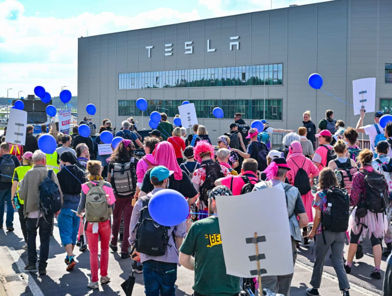 Environmental activists walk past the Tesla plant during a protest against Tesla. After sometimes violent clashes on May 10, 2024 at the Tesla factory site in Gruenheide near Berlin, new protests are currently underway against the US company. Patrick Pleul/dpa