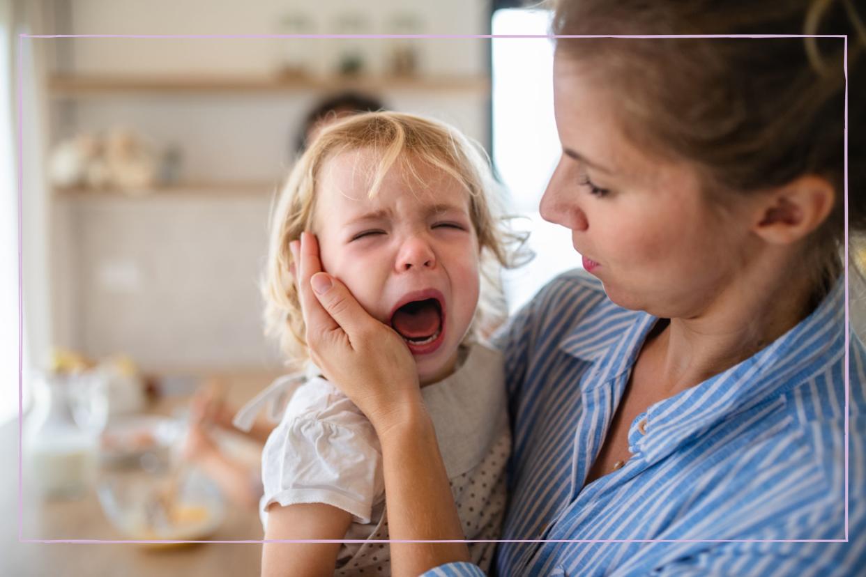  A woman carrying a crying toddler. 