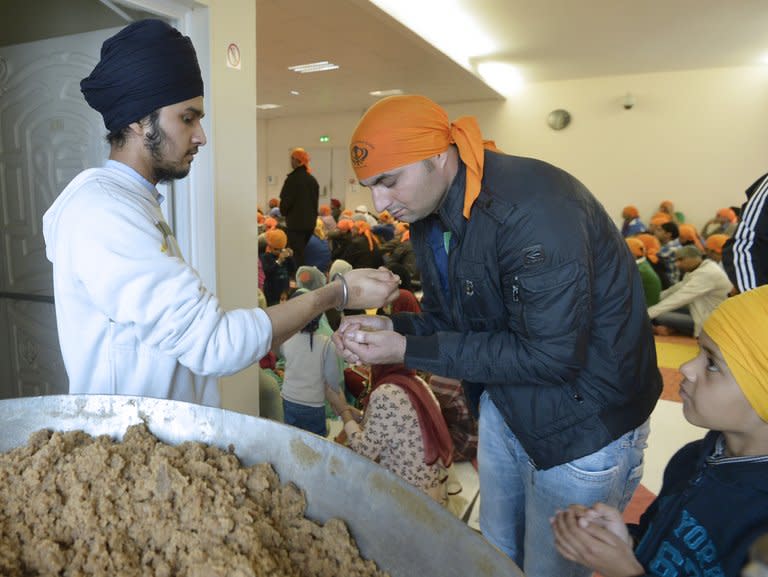 Faithful from the Paris Sikh community receive the "parshad" (a wheat flour, butter and sugar semolina halva) on September 22, 2013 at a temple in Paris