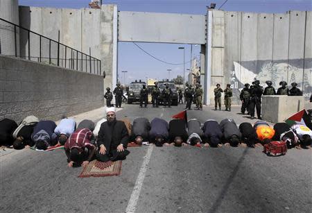 Palestinians attend Friday prayers in front of Israeli troops during a protest calling for the release of Palestinian prisoners held in Israeli jails, near an Israeli checkpoint in the West Bank town of Bethlehem April 4, 2014. REUTERS/Ammar Awad