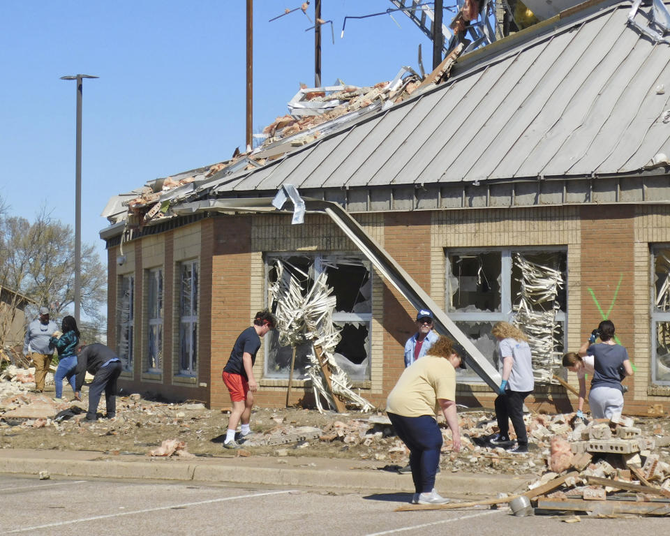 Volunteers clean up at Wynne High School, Saturday, April 1, 2023, near the front entrance of the school on E. Jackson Avenue in Wynne, Ark., following severe weather the previous night. (Nena Zimmer/The Jonesboro Sun via AP)