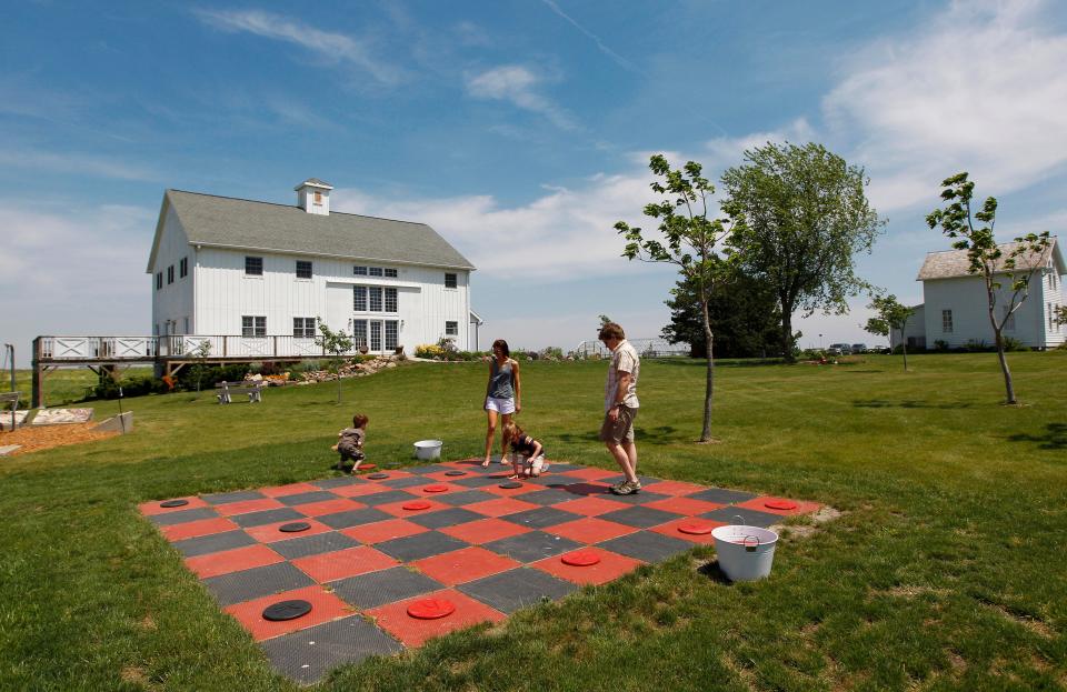 A family enjoys a game of checkers outside The Gathering Table on the grounds of the Henry A. Wallace Country Life Center near Orient.