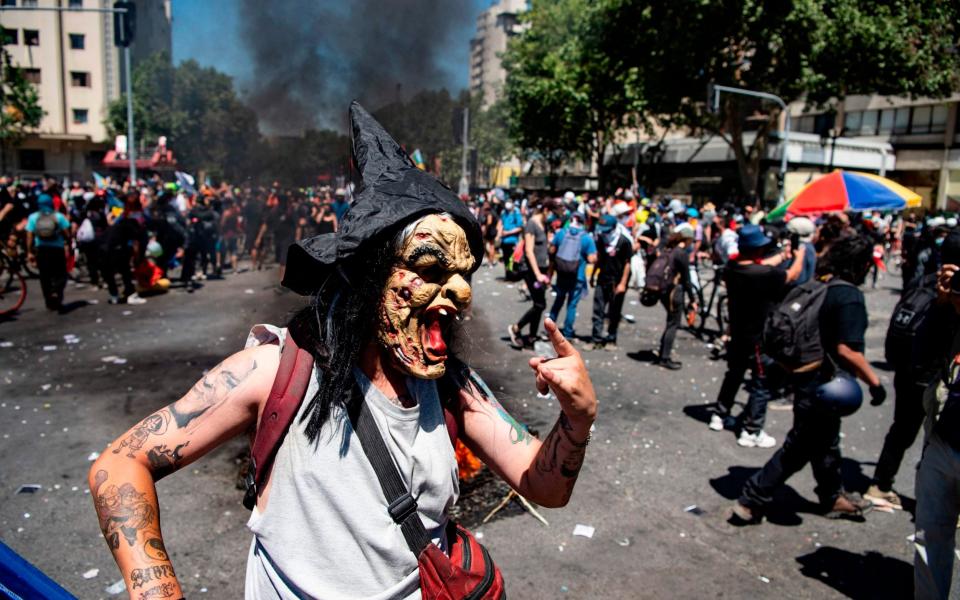 A demonstrator wearing a witch mask commemorates the first anniversary of the social uprising in Chile - AFP