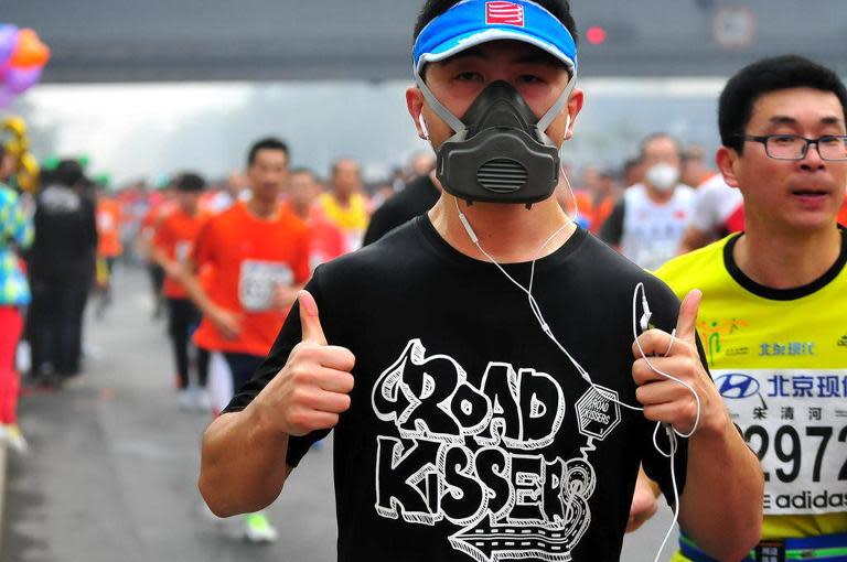 A runner wears a gas mask as he takes part in the 34th Beijing International Marathon which began at Tiananmen Square in Beijing on October 19, 2014