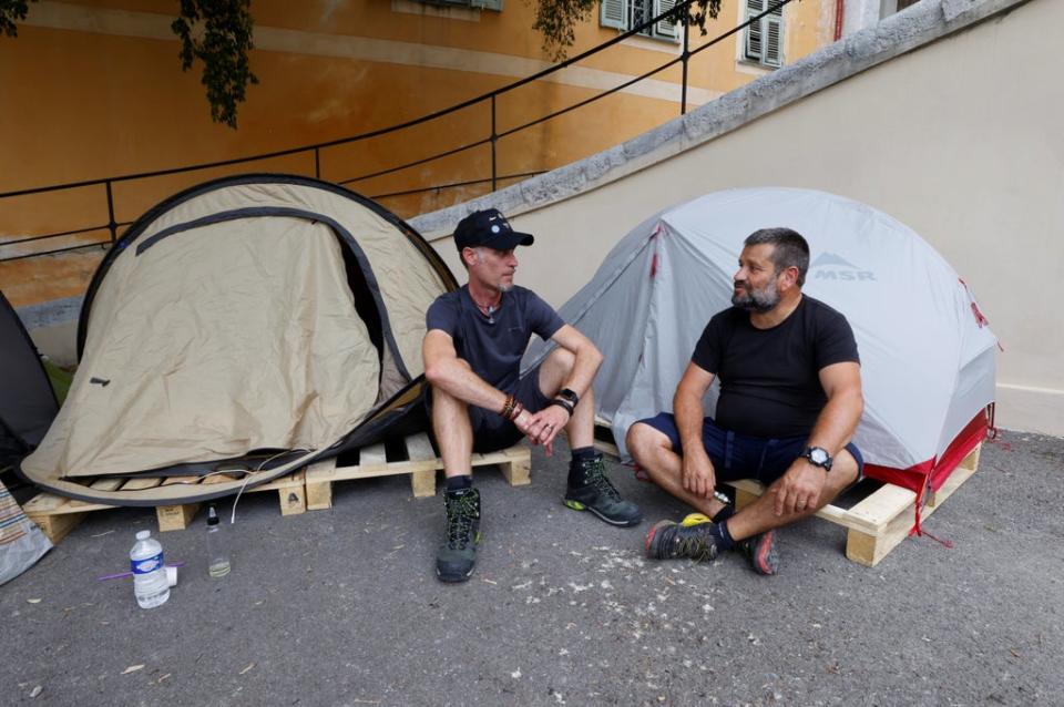 Thierry Paysant, a security worker and firefighter at the Pasteur hospital, and Christophe, a carer at the same hospital, sit in front of their tents near the Abbaye Saint-Pons in Nice during a hunger strike to protest against France’s restrictions, including compulsory health passes (REUTERS)