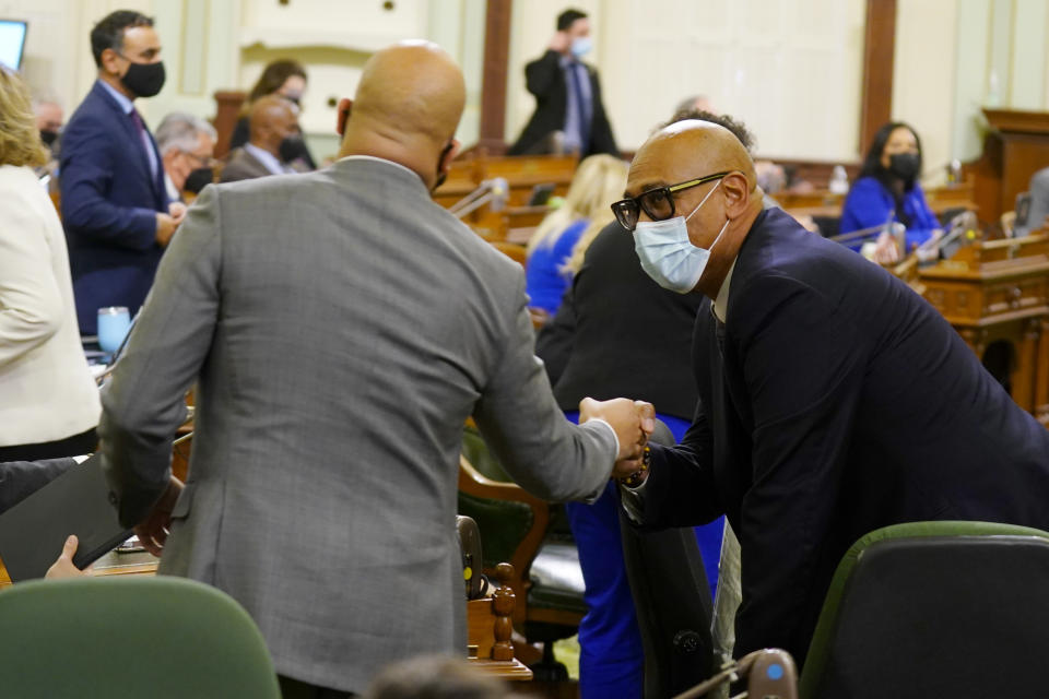 Democratic Assemblyman Chris Holden, right, receivers congratulations from fellow Democratic Assemblyman Isaac Bryan, after his fast food employee measure was approved by the Assembly in Sacramento, Calif., Monday, Jan. 31, 2022. California's more than half-million fast food workers would get increased power and protections under Holden's first-in-the-nation measure.(AP Photo/Rich Pedroncelli)