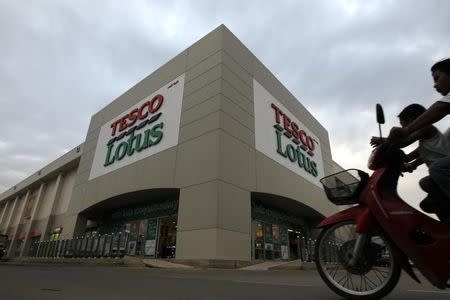 A man rides a motorbike with his son outside a Tesco Lotus supermarket in Bangkok January 12, 2012. REUTERS/Sukree Sukplang