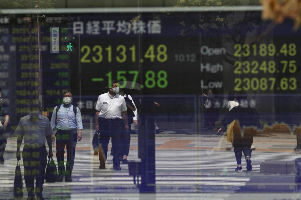 People wait at a traffic intersection, reflected on a monitor showing Japan's Nikkei 225 index at a securities firm in Tokyo on Monday, Aug. 17, 2020. Japanese stocks sank while other Asian markets gained Monday after Japan reported a record economic contraction as the coronavirus pandemic weighed on retailing, investment and exports.(AP Photo/Hiro Komae)