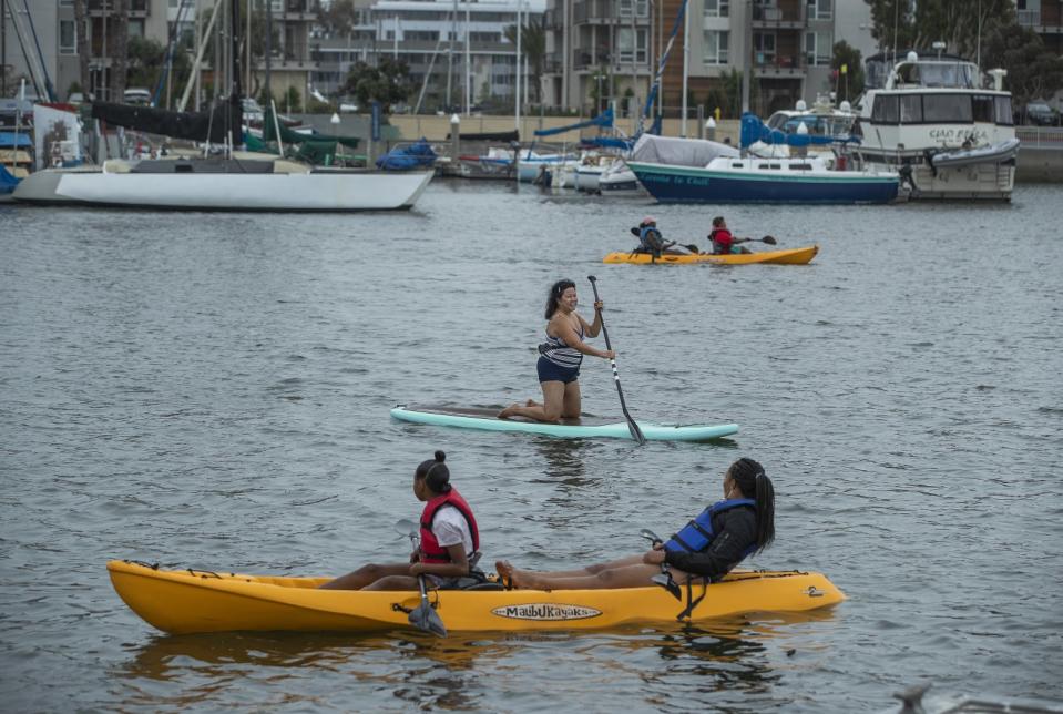 People paddle along in their kayaks and paddle board, center, during a visit to Marina Beach, also known as Mother's Beach