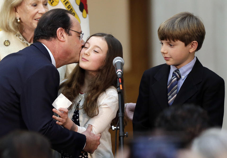 French president Francois Hollande, left, kisses a girl on the stage during a visit to city hall on Wednesday, Feb. 12, 2014, in San Francisco. Hollande is visiting San Francisco to meet politicians, lunch with Silicon Valley tech executives and inaugurate a new U.S.-French Tech Hub. (AP Photo/Marcio Jose Sanchez)