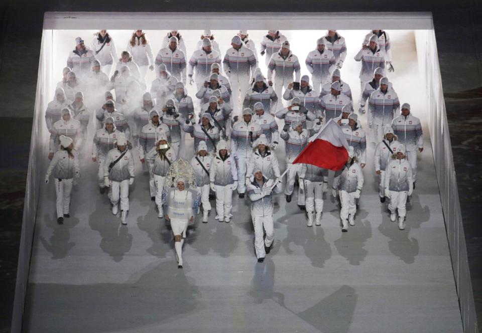 Dawid Kupczyk of Poland holds his national flag and enters the arena with teammates during the opening ceremony of the 2014 Winter Olympics in Sochi, Russia, Friday, Feb. 7, 2014. (AP Photo/Charlie Riedel)