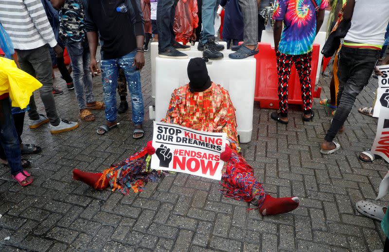 A demonstrator covering his face carries a banner during a protest over alleged police brutality, in Lagos