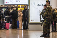 Soldiers patrol as passengers walk through the departure terminal during the one-year anniversary service at Zaventem Airport in Brussels on Wednesday, March 22, 2017. The suicide bombings at the Brussels airport and subway on March 22, 2016, killed 32 people and wounded more than 300 others. (AP Photo/Geert Vanden Wijngaert)