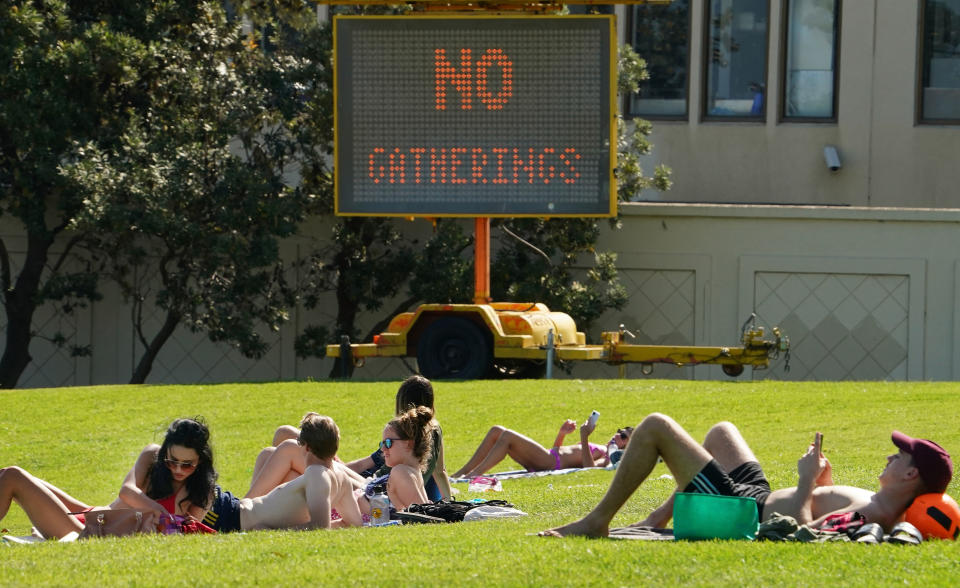 People sunbathe at St Kilda Beach in Melbourne, Saturday, March 28, 2020.